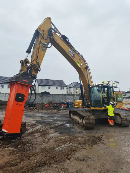 NPK breaker on a Cat excavator alongside site plant