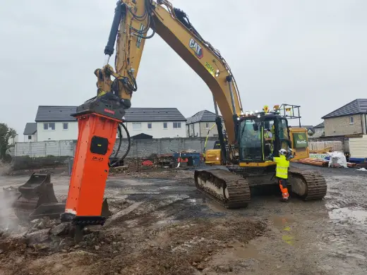 Hydraulic breaker working beside a groundworker on site