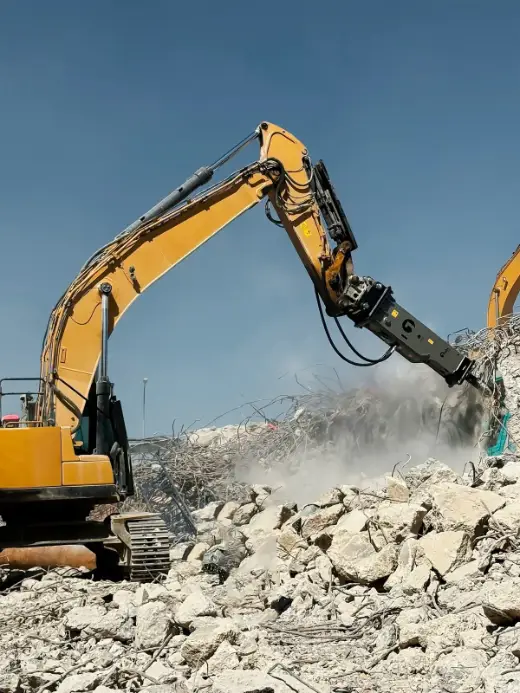 Hydraulic breaker on demolition work with concrete dust flying
