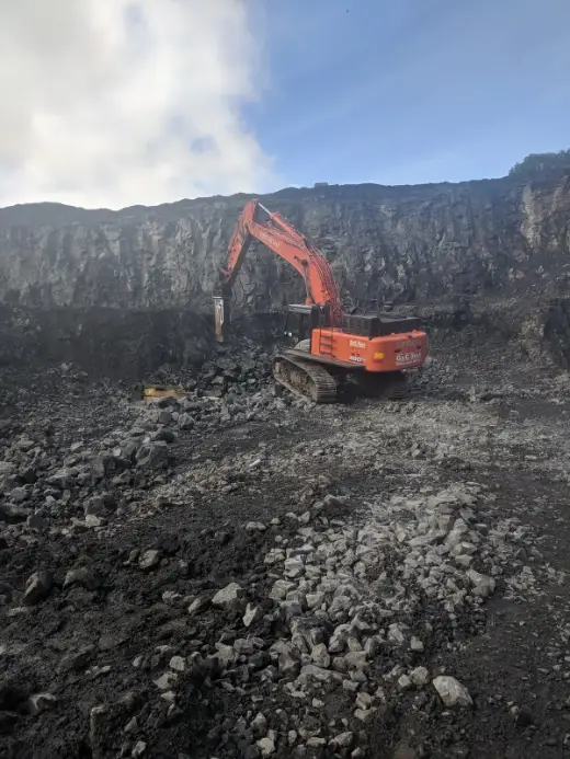 Excavator and breaker working a quarry floor