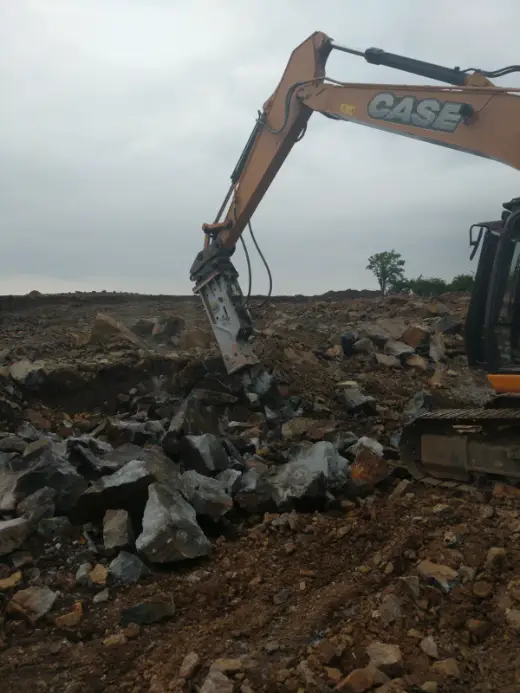 Hydraulic breaker splitting rock on site