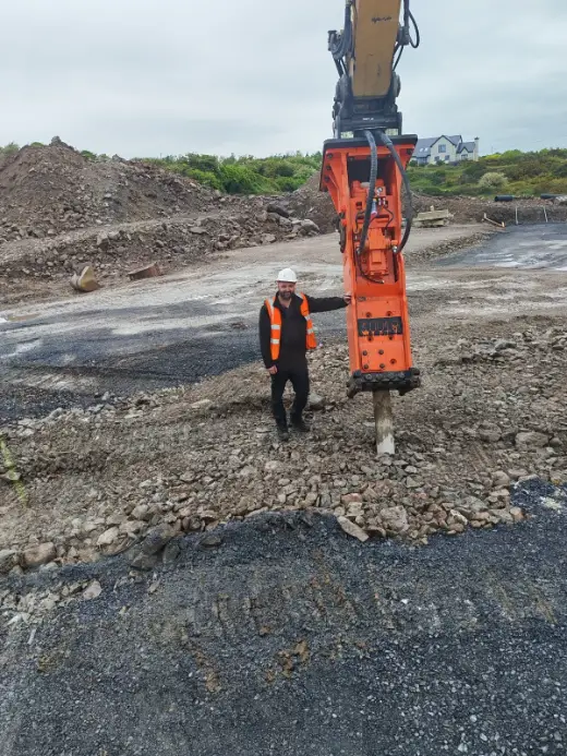 Hydraulic breaker in a quarry with an operator alongside