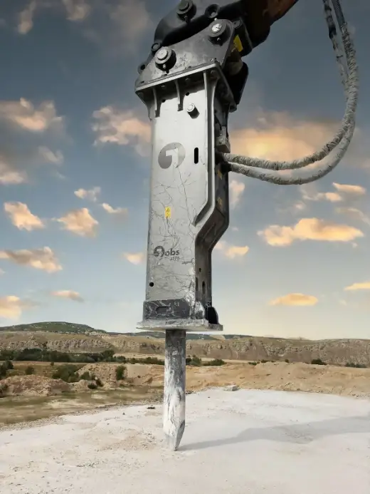 Hydraulic breaker on an excavator against an evening sky