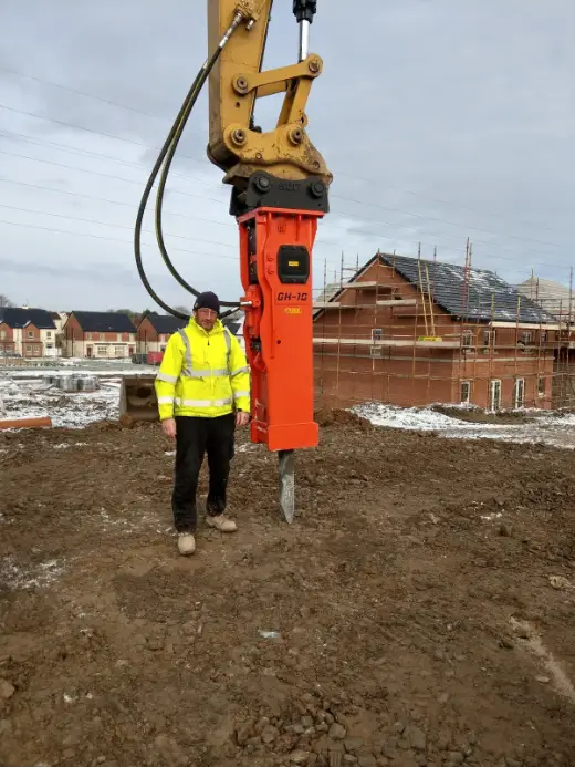 Hydraulic post driver and operator on a housing site